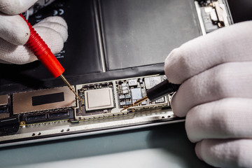 Close up hands of a service worker repairing modern tablet computer.