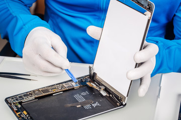 Close up hands of a service worker repairing modern tablet computer.