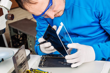 Close up hands of a service worker repairing modern tablet computer.