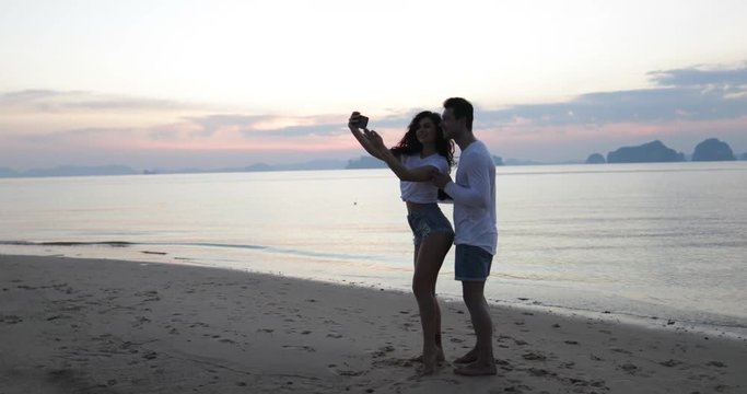 Young Couple Taking Selfie Photo On Beach At Sunset, Man And Woman Walking Seaside, Tourists Sea Vacation Slow Motion 60