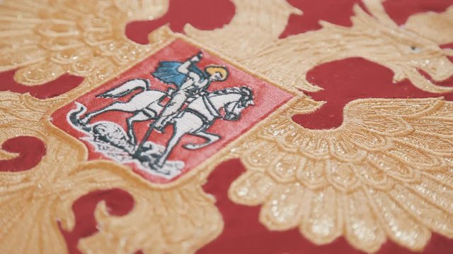 Flag of the Russian Federation: George the Victorious on a red background. Two-headed golden eagle on a red background: embroidery of the flag of the Russian Federation.