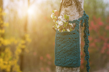 Boho bag crochet. Handmade knitted blue linen Pocket bag on spring nature background. Womans vintage accessories.