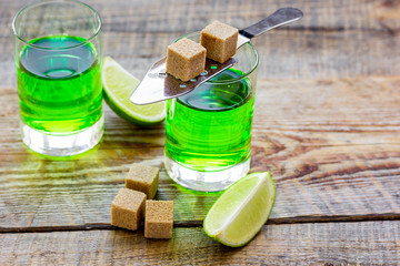 absinthe with sugar cubes in spoon on wooden background
