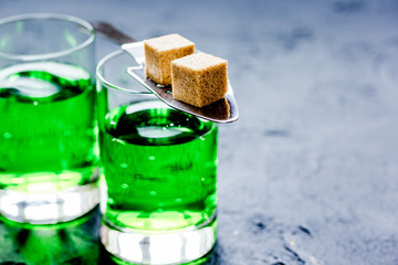 absinthe with sugar cubes in spoon on dark background