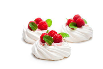 Mini  Pavlova meringue nests with berries and mint on isolated on white