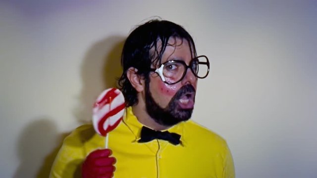 A weird salesman hiding his face under a lollipop. Close-up shot. Funny comedy foolish characters.

