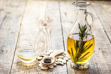 oil in carafe with pepitas and rosemary on wooden background mock-up