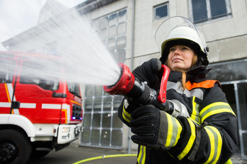 Obraz premium Junge Feuerwehrfrau löscht ein Feuer