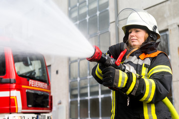 Fototapeta premium Junge Feuerwehrfrau löscht ein Feuer