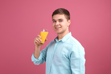 Young man drinking juice on color background