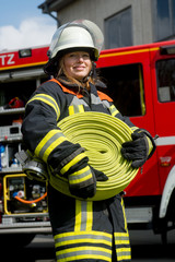 Obraz premium Junge Feuerwehrfrau trägt einen Schlauch