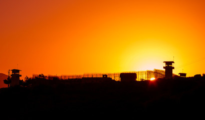 Silhouette of barbed wires and watchtower of prison.