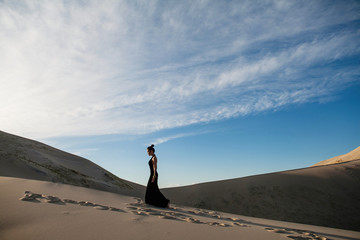 Beautiful woman in a long black dress desert landscape