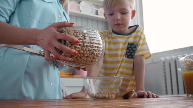 Mom Son Spend Time Holiday Eating Breakfast, mother and boy child on kichen, happy family, child eating milk corn flakes