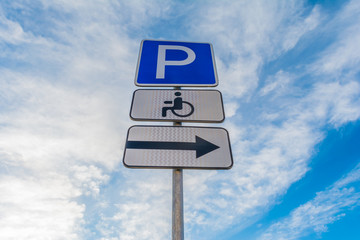 Metal support with traffic signs parking place, right signboard, sign of a place for the disabled against a blue sky with white clouds, abstract background