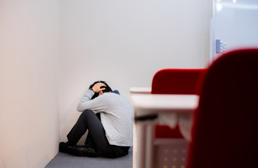 部屋の隅で落ち込む男性