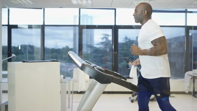  Man using treadmill in modern gym with view of natural environment on video screen. 