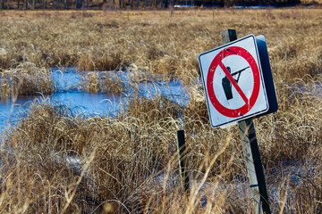 Shot up No Shooting sign along a nature path