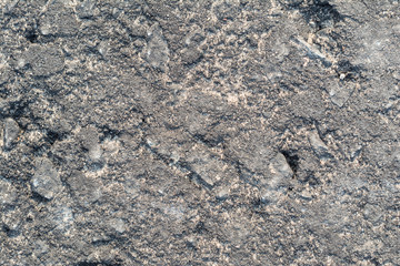 Surface texture of road asphalt with a lot of cracks, cracks, dents and potholes close-up