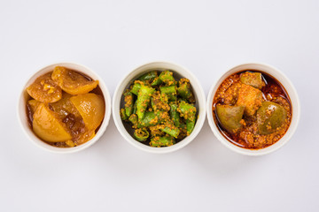 Group photograph of indian pickles like mango pickle , lemon pickle and green chilli pickle, sarved in ceramic bowls, selective focus