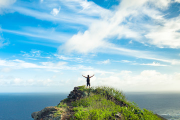 Feeling free! Healthy and fit active lifestyle concept.  Male hiker standing on mountain peak celebrating. 
