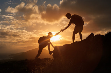 Male and female hikers climbing up mountain cliff and one of them giving helping hand. People helping and, team work concept.


 - Powered by Adobe