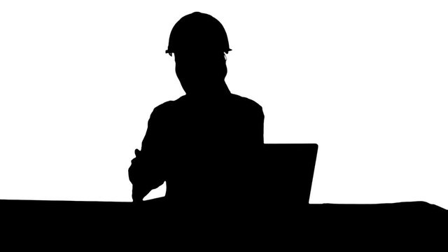 Silhouette Woman in orange hardhat calling the phone discussing constraction plan.