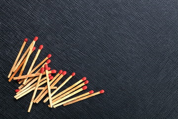 Matchsticks put on the black color leather surface as a background represent the flammable material.