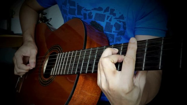Man's hands playing classical guitar, close up