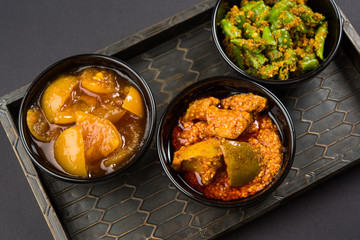 Group photograph of indian pickles like mango pickle , lemon pickle and green chilli pickle, sarved in ceramic bowls, selective focus © StockImageFactory