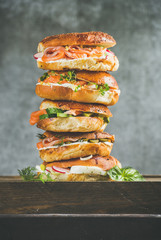 Heap of Bagels with salmon, eggs, vegetables, capers, fresh herbs and cream-cheese, grey concrete...