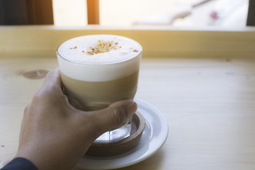 man hands holding grass of hot drink that standing on wooden table