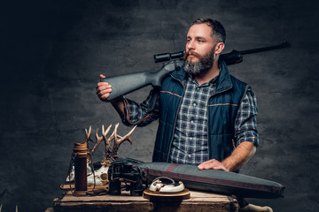 Bearded modernl hunter with his trophy holds a rifle.