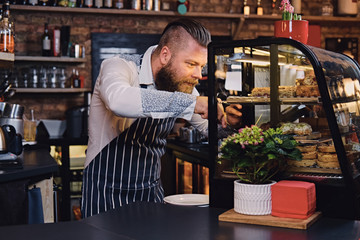 A man holds chocolate cake at the counter in the bakery shop.