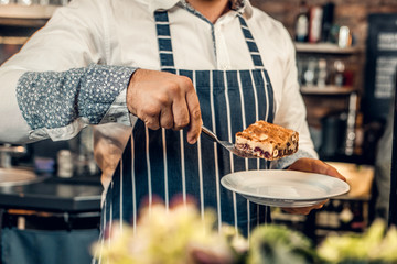 A man holds chocolate cake at the counter in the bakery shop.
