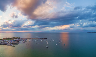 Aerial panorama of cloudscape over long pier and moored boats at sunset