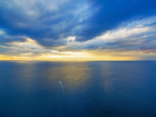 Obraz premium Aerial view of lonely boat sailing across ocean at beautiful sunset