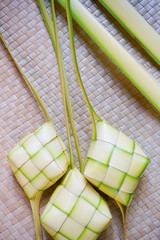 Ketupat (rice dumpling) is a local delicacy during the festive season in Malaysia on traditional mat background. Ketupat, a natural rice casing made from young coconut leaves for cooking rice.