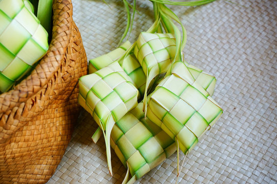 Ketupat (rice dumpling) is a local delicacy during the festive season in Malaysia on traditional mat background. Ketupat, a natural rice casing made from young coconut leaves for cooking rice.