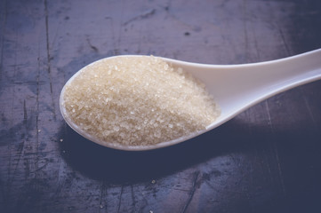 Fototapeta na wymiar sugar on white spoon on wooden table
