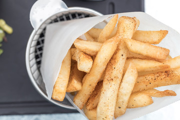 Potatoes fries in a little white paper bag on wood board