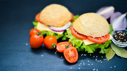 Hamburger with cheese, meat, tomatoes and onions and herbs. On Wooden background. Top view. Free space.