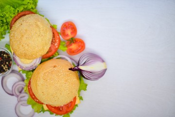 Hamburger with cheese, meat, tomatoes and onions and herbs. On Wooden background. Top view. Free space.