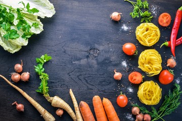 Pasta with vegetables, cherry tomatoes, chili peppers and garlic. On a wooden background. Free space for text . Top view.