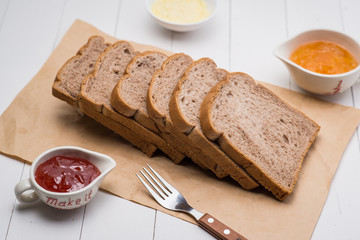 Close-up of slice of toast bread with jam and butter on wood table