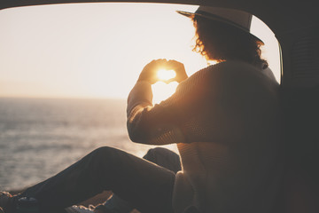 Young traveling female sitting in hat in the trunk of van and enjoing the adventure, woman hipster...