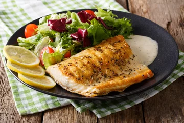 Fotobehang Grilled char fillet with mixed salad and sauce on a plate close-up. horizontal © FomaA