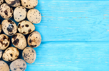 Scattered raw quail eggs on wooden background, top view