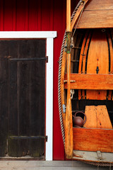 Red fishing hut with black door and wooden row boat in Swedish archipelago