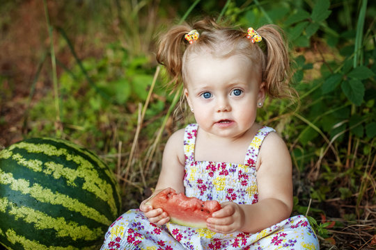A little girl sitting and eating watermelon. The concept of child development and healthy food.